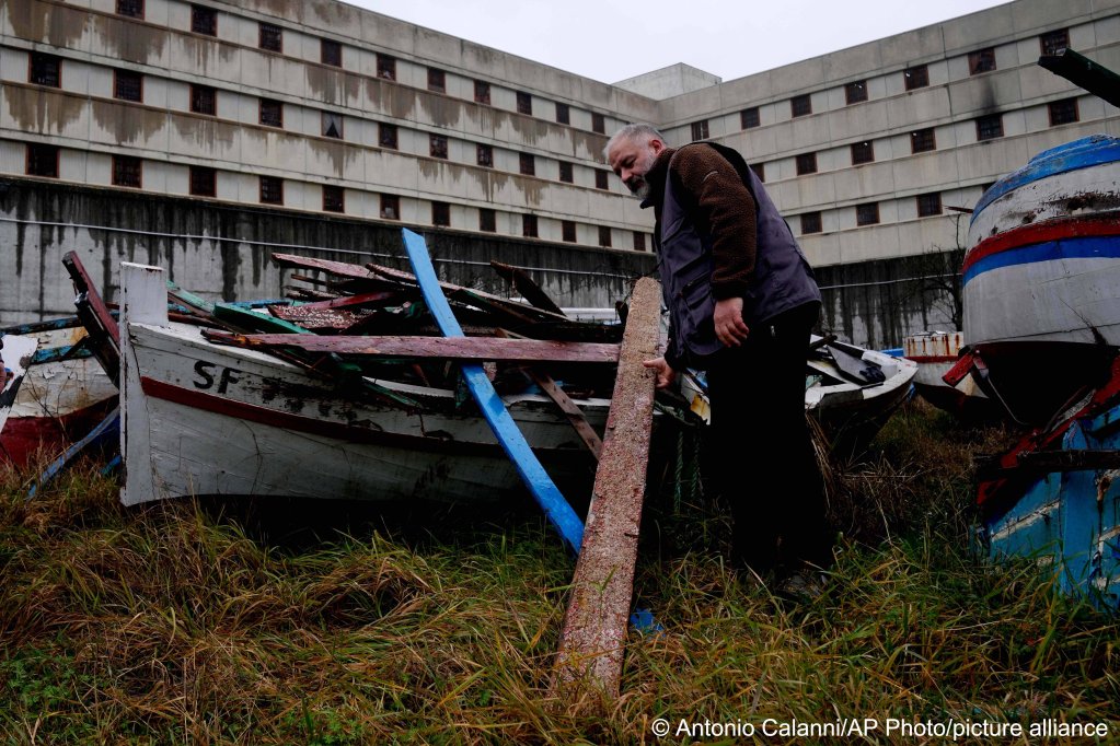 Inmate Andrea Volonghi checks the wood of a wrecked migrants' boat stored in the prison facilities | Photo: Antonio Calanni /AP Photo