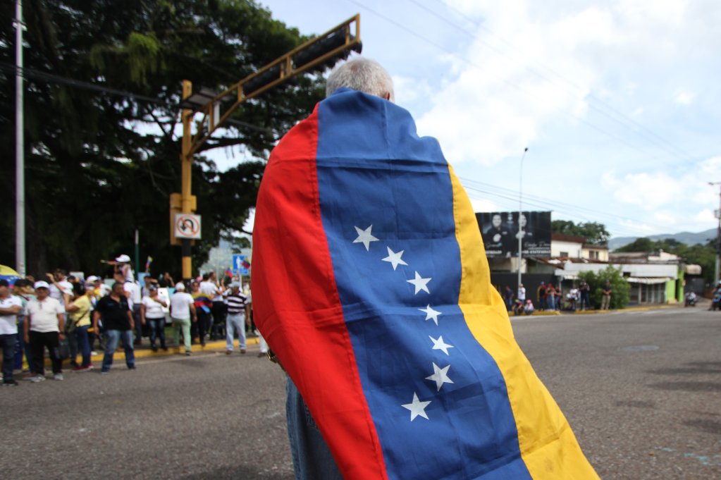 A person draped with the Venezuelan flag protests during an opposition rally in San Cristobal, Venezuela on August 3, 2024. Photo: Jorge Mantilla/NurPhoto