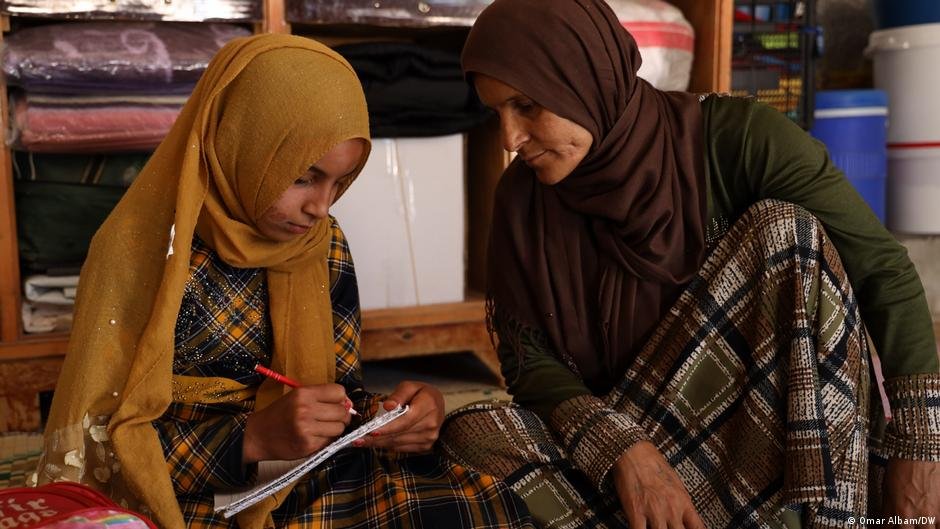 Fatima has been going to school for about four years, walking around a kilometre each day because the school is outside the camp. Her mother, who prefers not to have her name published, helps her with homework. | Photo: Omar Albam/DW