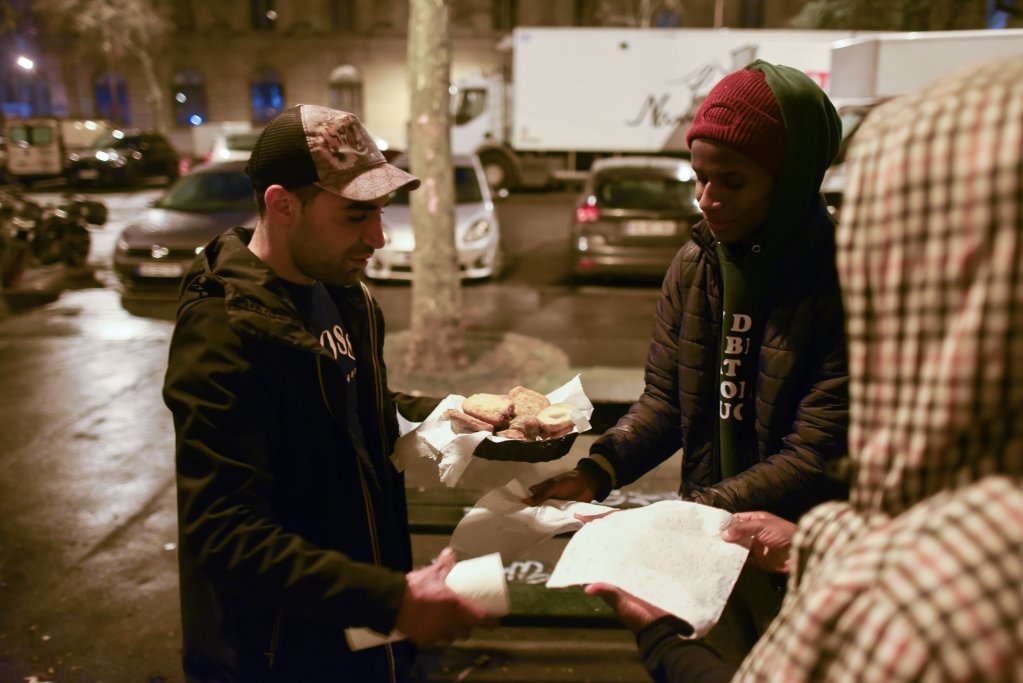 A neighbor approaches with vegetable galettes for homeless young people, on March 30, 2023. Photo: Mehdi Chebil.