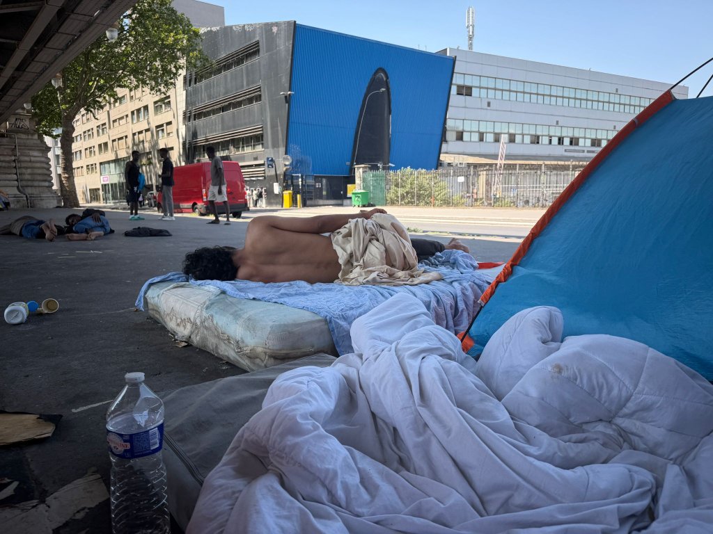 À l'ombre sous le métro Stalingrad, des exilés dorment à même le sol ou sur des matelas. Ils sont torses nus pour avoir moins chaud en pleine canicule. Crédit : InfoMigrants