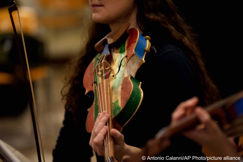 A woman member of the 'Sea Orchestra' rehearses with violin made from the wood of wrecked immigrants' boats in Milan, northern Italy, Saturday, Feb. 10, 2024 | Photo: Antonio Calanni /AP Photo