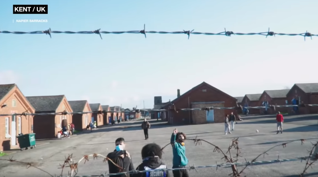 A screenshot of the Napier Barracks through the fence for a RT report | Source: Screenshot RT