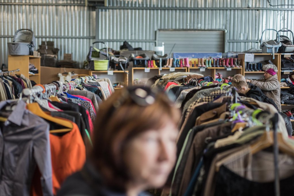A woman standing in front of clothes racks inside a warehouse of Latvian NGO Tavi Draugi in Riga | Photo: Martin Thaulow