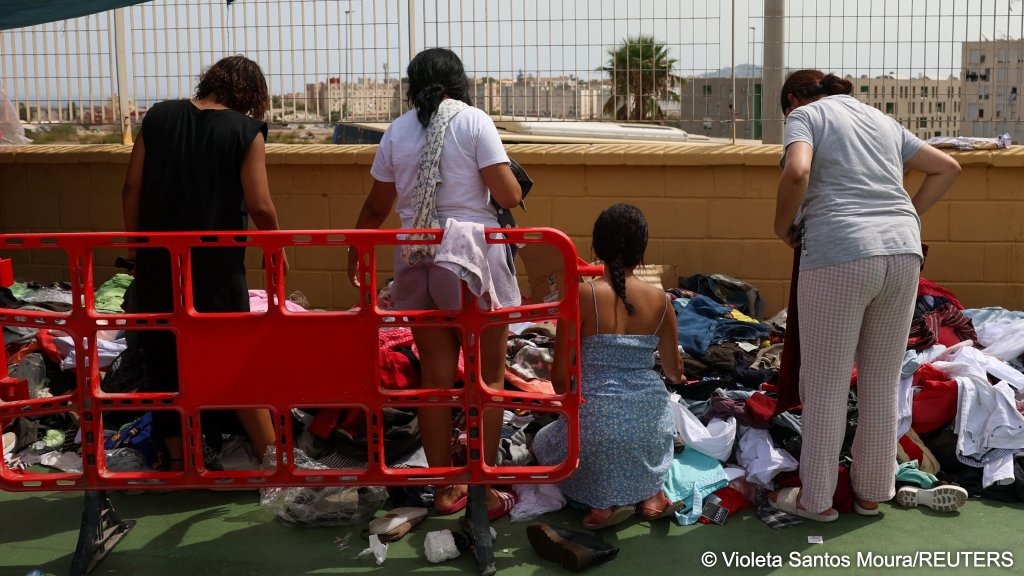 Migrant women and children pick from donated clothes in a sports field set up by local residents as an improvised shelter for women and children | Photo: Violeta Santos Moura/REUTERS