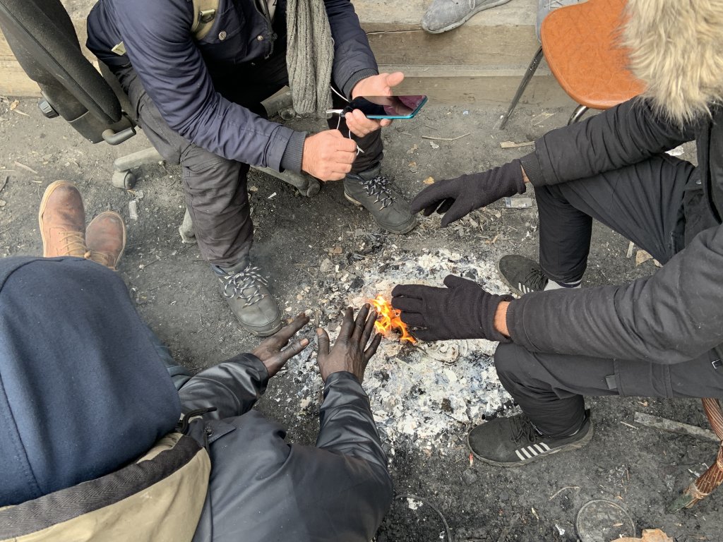Des migrants tentent de se réchauffer autour d'un feu de camp, mercredi 14 décembre, boulevard La Chapelle, à Paris. Crédit : InfoMigrants.
