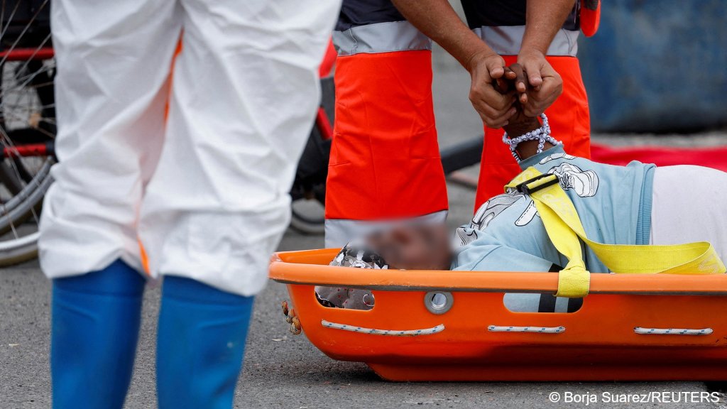 A Red Cross doctor holds the hand of a migrant arriving in the port of Arguineguin, on Gran Canaria on June 19 | Photo: Borja Suarez / Reuters