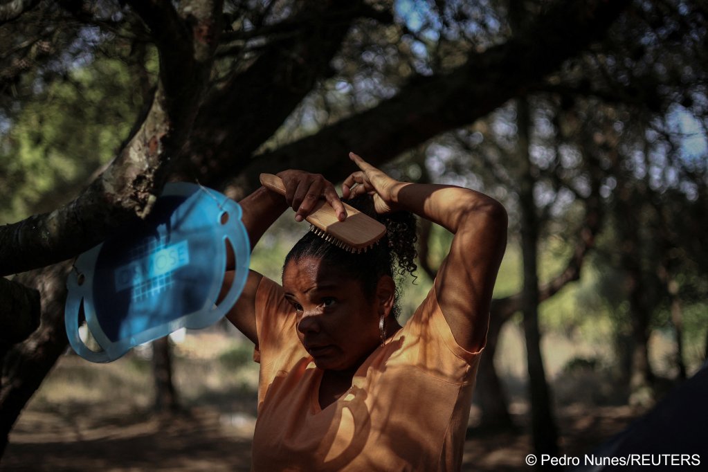 Andreia Costa, 50, from Sao Paulo, Brazil, arranges her hair at the improvised campsite in a field where she lives in Carcavelos, in Cascais, Portugal, October 11, 2023 | Photo: Pedro Nunes / Reuters