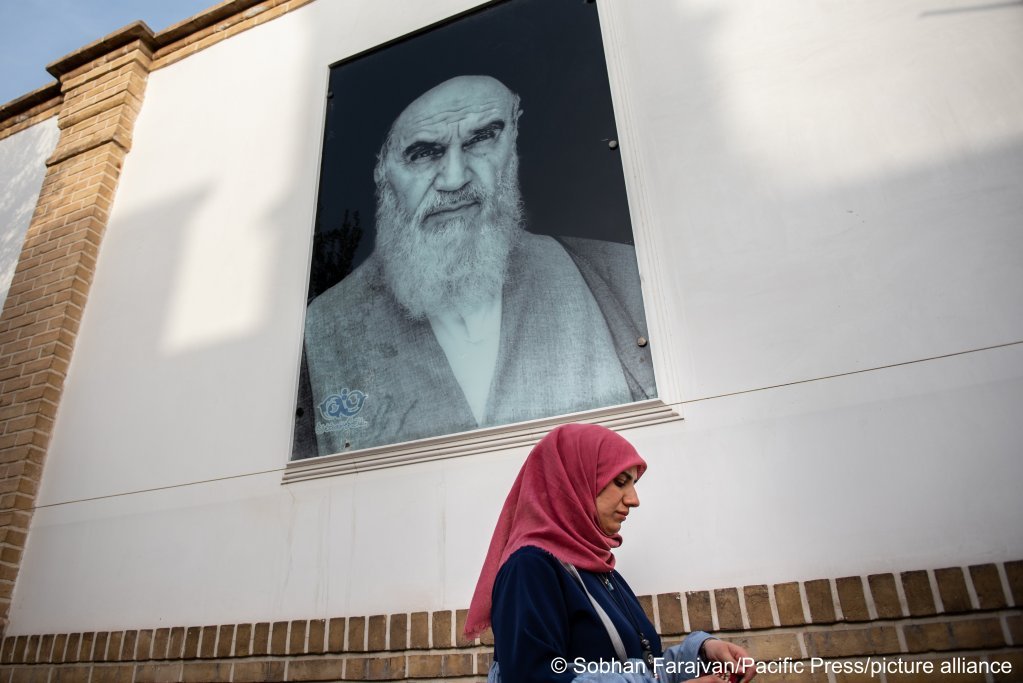 یک زن از کنار تصویر آیت الله خمینی در شهر قٌم می‌گذرد
Photo : Sobhan Farajvan/Pacific Press/picture-alliance