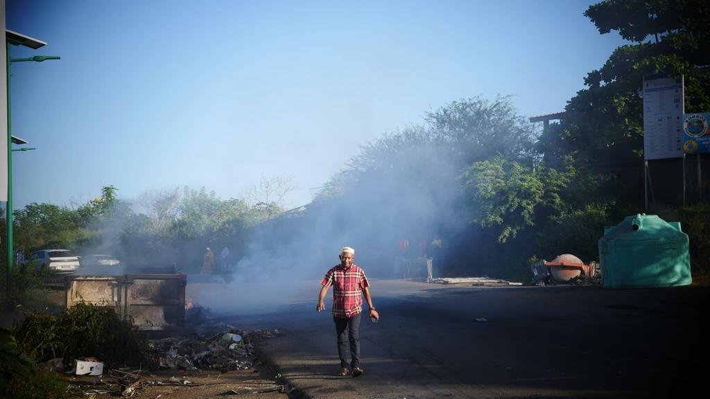 Un habitant de Mayotte marche dans la fumée d'une barricade sur la route nationale, à Majicavo, mardi 25 avril. Crédit : Romain Philips/InfoMigrants