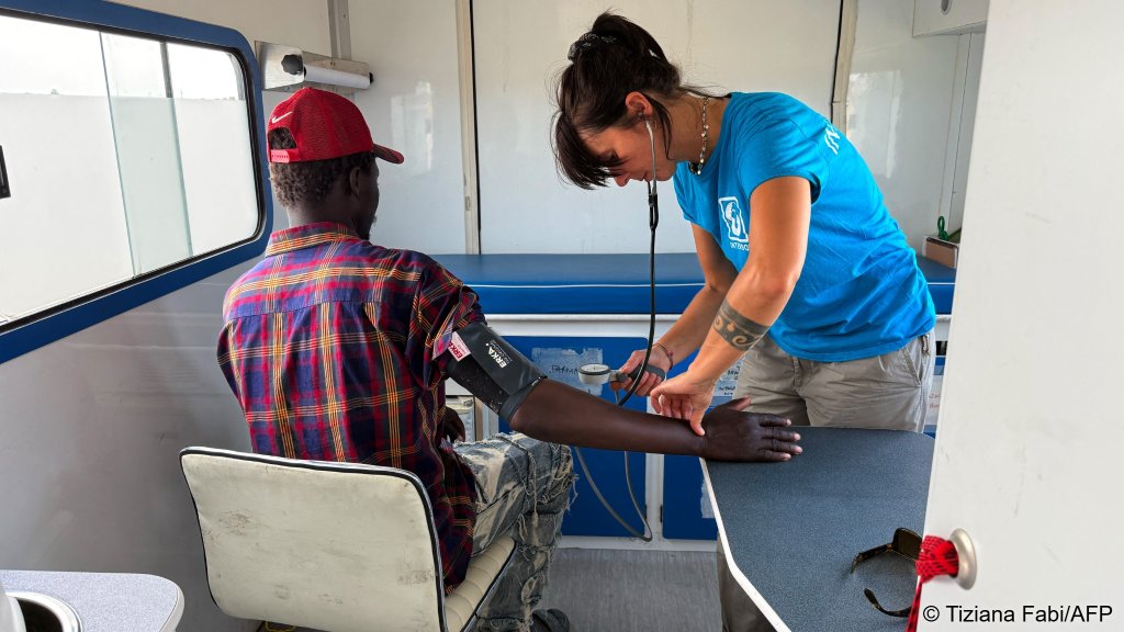 Italian medic with NGO Intersos, Camilla Faragona, checks a man's blood pressure in a van parked outside the Borgo Mezzanone makeshift camp on June 23, 2026 | Photo: AFP