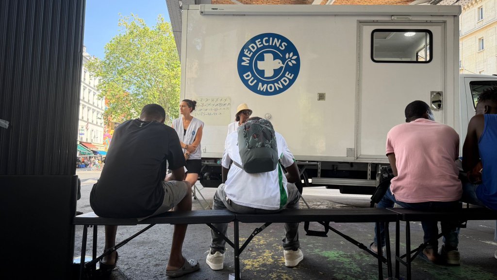 Des membres de l'association Médecins du Monde apporte les premiers soins à des hommes du campement. La majorité d'entre eux souffrent de la chaleur. Crédit : InfoMigrants