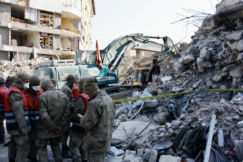 Des gendarmes bloquent l'accès aux décombres pendant que des secouristes cherchent des survivants et des corps dans un immeuble effondré d'Antakya, le 14 février 2023. Crédit : InfoMigrants