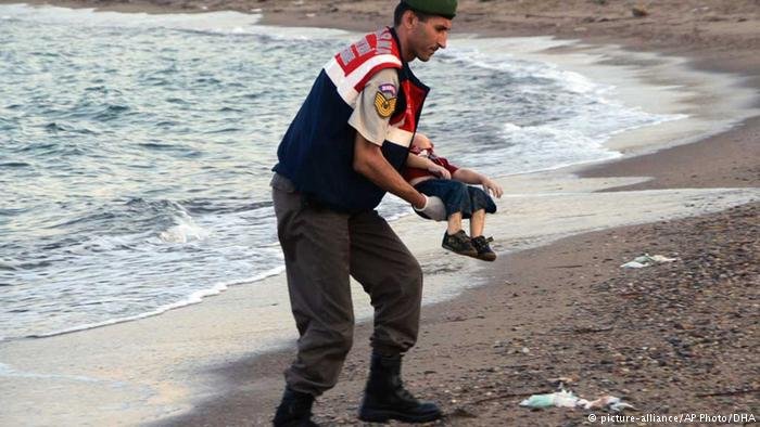 A man carries the body of Syrian toddler Alan Kurdi on a beach in Kos in 2015 | Photo: picture-alliance / AP Photo / DHA