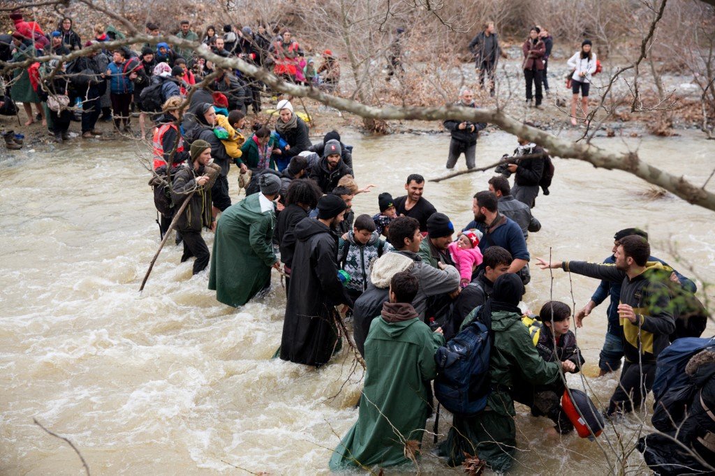 Migrants and refugee cross a river on their way to Macedonia from a makeshift camp at the Greek-Macedonian border, near the Greek village of Idomeni on March 14, 2016. Photo: AFP