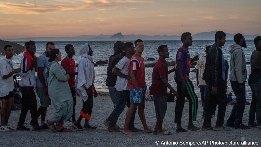 Migrants who crossed from Morocco into Spain line up for food distribution on a beach in the Spanish enclave of Ceuta, Monday, August 3, 2026 | Photo: Antonio Sempere / AP Photo / picture alliance