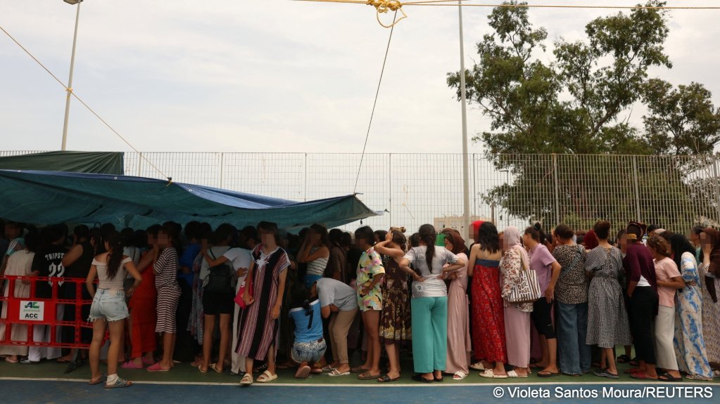 Migrant women and children await a donated meal in a sports field set up by local residents as an improvised shelter for women and children | Photo: Violeta Santos Moura/REUTERS