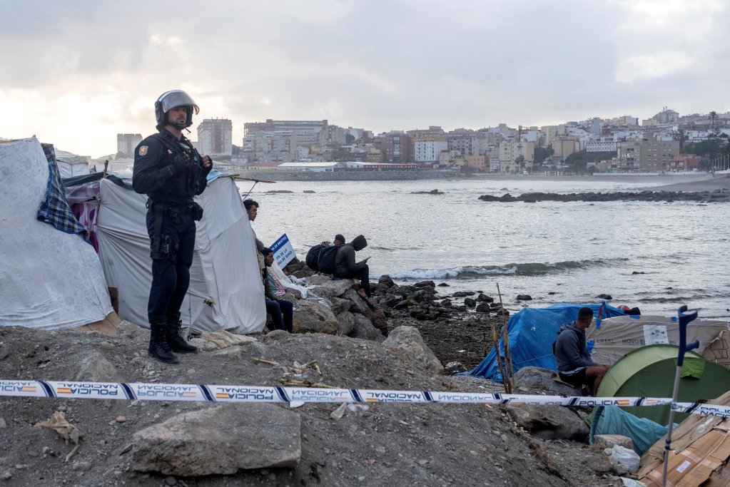 An officer looks on as riot police clear part of the makeshift migrant camp at Benitez beach, Ceuta after the arrival of an estimated 70,000 people | Photo: Manu Brabo / Reuters