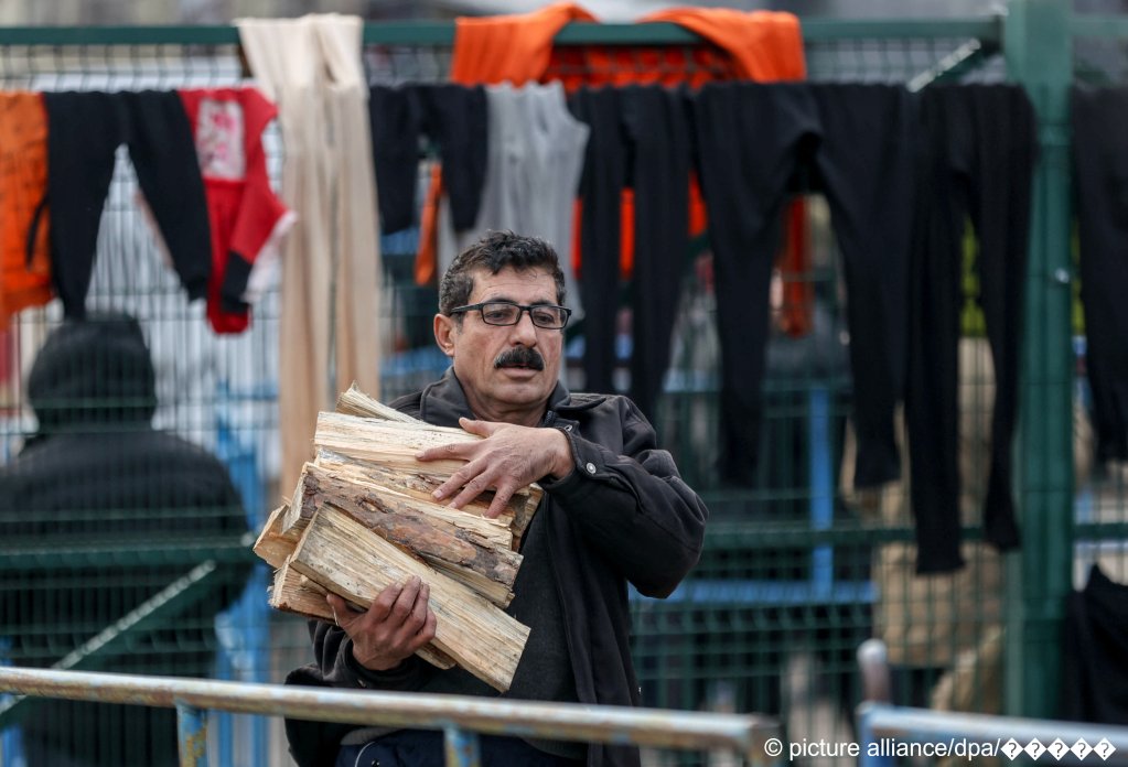  A migrant carries firewood outside the Bruzgi transport and logistics center on November 22, 2021 | Photo: Andrei Pokumeiko/BelTA/TASS/picture-alliance
