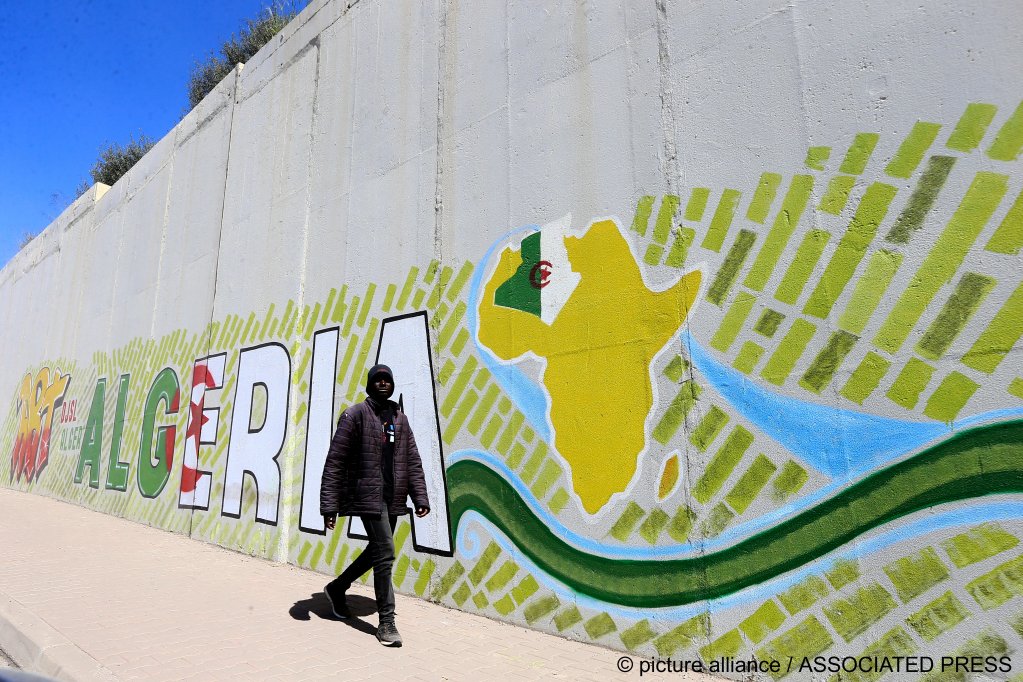 From file: A migrant walks past a mural in Algiers in 2023 | Photo: Fateh Guidoum / picture alliance / ASSOCIATED PRESS