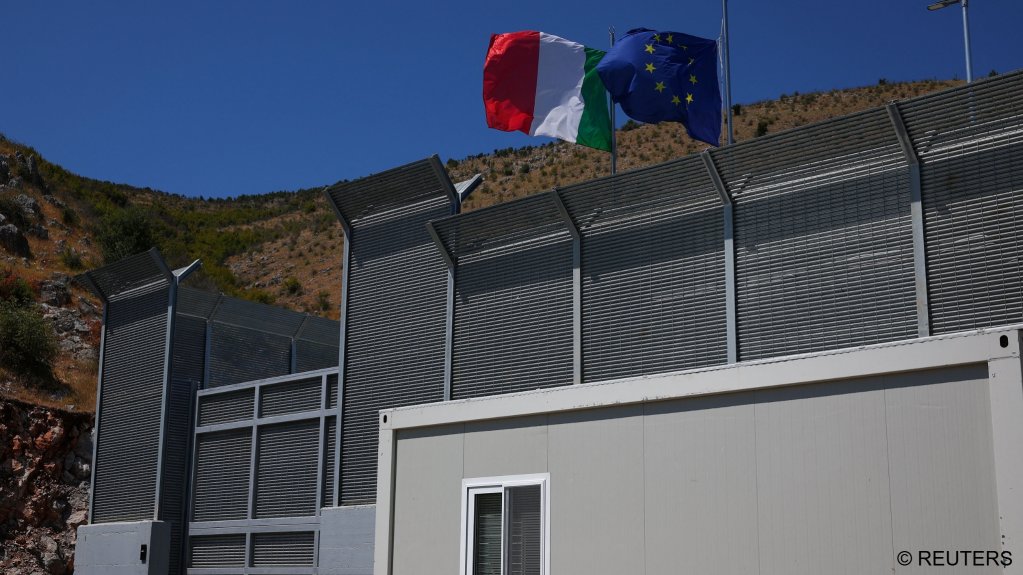 File photo: An Italian and a European Union flag flutter at a migrant detention centre in Gjader, Albania | Photo: Florion Goga / Reuters