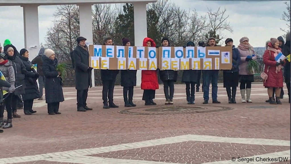 Citizens of Melitopol hold up a sign with their city written on it in the colors of the Ukrainian flag in early March | Photo: Sergei Cherkes / InfoMigrants / DW
