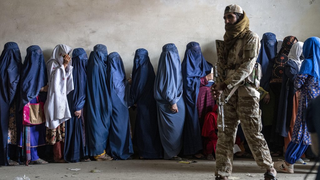 File photo: A Taliban fighter stands guard as women wait to receive food rations distributed by a humanitarian aid group, in Kabul, Afghanistan | Photo: Ebrahim Noroozi / AP Photo 
