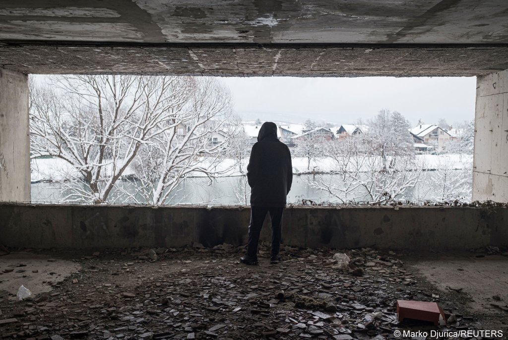 A migrant looks out of a window on January 11, 2021 as hundreds of them are taking shelter in abandoned buildings in the northwestern town of Bihac in Bosnia and Herzegovina | Photo: Marko Djurica/Reuters