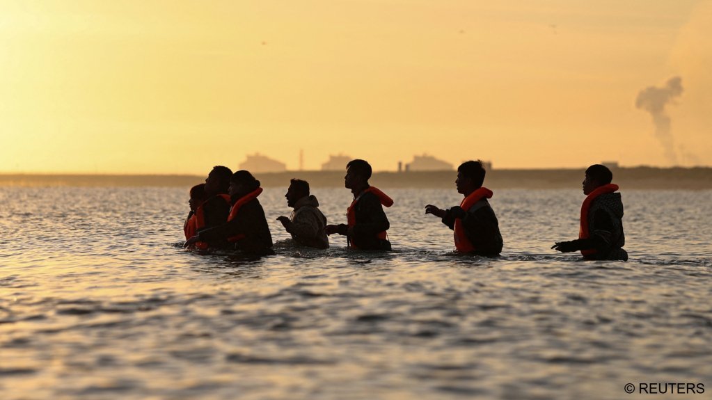 File photo. A group of migrants walk into the water to reach an inflatable dinghy in an attempt to leave the coast of northern France and to cross the English Channel | Photo: Reuters