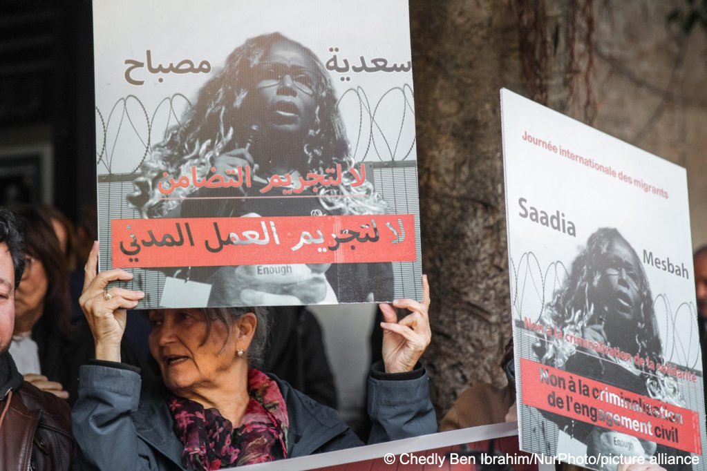 Sana Ben Achour, an academic, jurist, and Tunisian activist, shouts slogans as she holds up a placard featuring a portrait of Saadia Mosbah reading in Arabic 'no to the criminalization of civil work' during a rally that brought together relatives, human rights organizations, and civil society groups outside the Court of First Instance in Tunis, Tunisia, on December 22, 2025 | Photo: Chedly Ben Ibrahim/NurPhoto