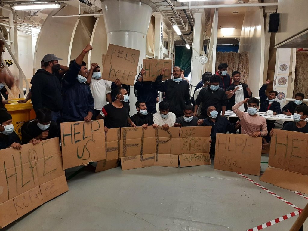 مهاجرون على متن سفينة "جيو بارنتس" يرفعون لافتات مدون عليها "ساعدونا" بسبب عدم إنزالهم. المصدر: أنسا. صورة من الأرشيف