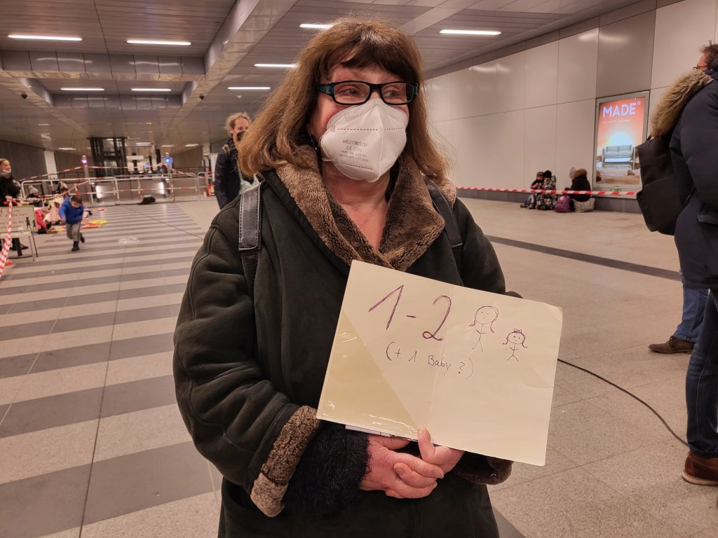 A local woman standing at a makeshift welcome area offering accommodation to refugees inside Berlin's main train station on March 7, 2022 | Photo: Benjamin Bathke/InfoMigrants
