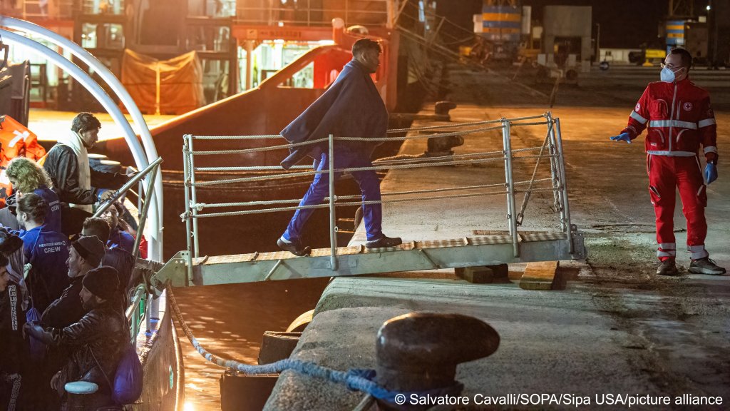 A migrant gets off the Mare Jonio ship, as Red Cross staff is seen welcoming him | Photo: Salvatore Cavalli / SOPA Images/Sipa USA