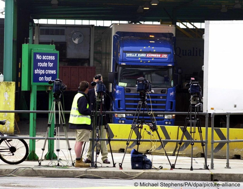Media congregate outside the custom's sheds on June 20, 2000, where the container holding irregular migrants was located at Dover Dock | Photo: Michael Stephens/dpa/picture-alliance