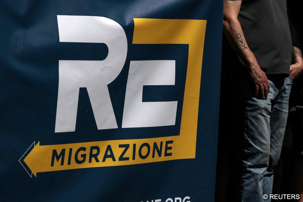 A participant stands beside a sign bearing the words “RE Migration” during a march organized by the “Remigration and Reconquest” committee in Rome, Italy, June 13 | Photo: Francesco Fotia / Reuters