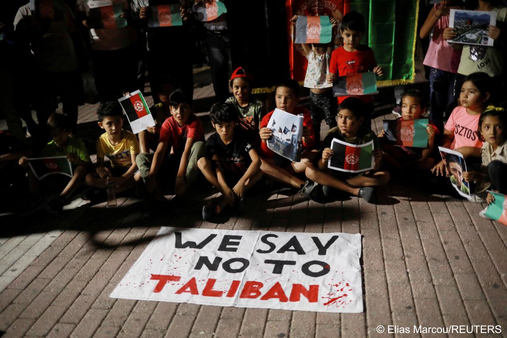 Children sit in front of a banner reading "We say No to Taliban" as Afghan migrants demonstrate against the Taliban takeover of Afghanistan, on the island of Lesbos, Greece, August 16, 2021 | Photo: REUTERS/Elias Marcou