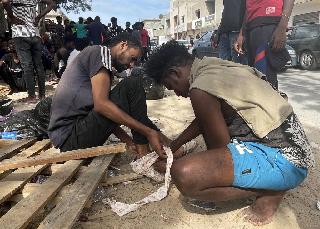 An injured African migrant being helped by another one during a sit-in to demand that the international community takes them out of Libya | Photo: ARCHIVE/EPA/STR
