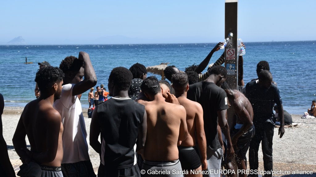 People thought to be migrants using a shower at a public beach in Ceuta to wash themselves and refill their water bottles on August 5, 2026 | Photo: Gabriela Sardá Núñez/EUROPA PRESS/dpa/picture alliance