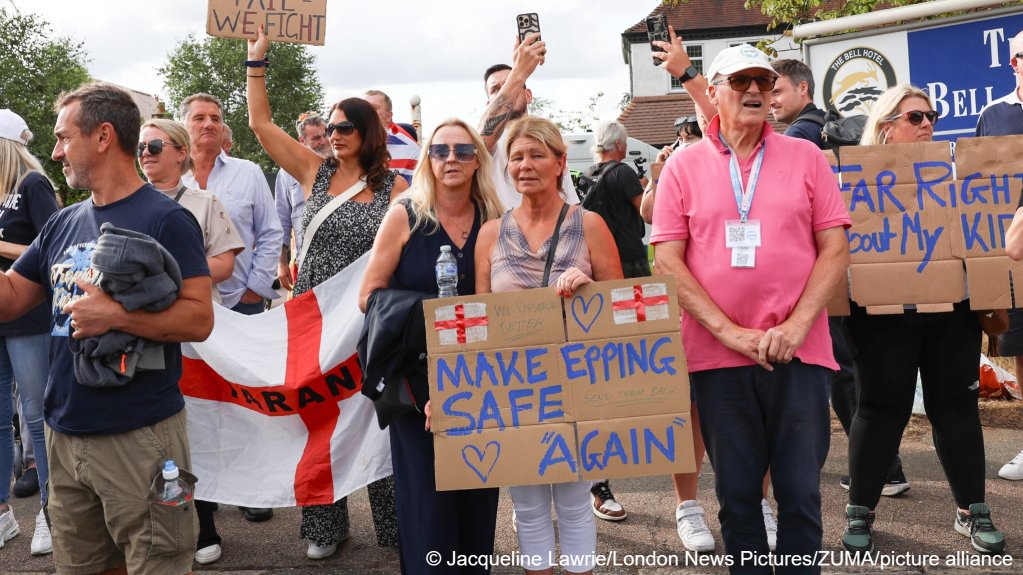 People holding placards, outside The Bell hotel in Epping, Essex, England, where local residents are protesting against the housing of migrants, July 20, 205 | Photo: Jacqueline Lawrie/London News Pictures via ZUMA Press Wire