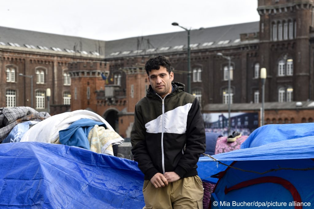 فریدون، یک پناهجوی افغان، در برابر یک اردوگاه که از خیمه ساخته شده است در مقابل مرکز ورود پناهجویان در بلجیم ایستاده است