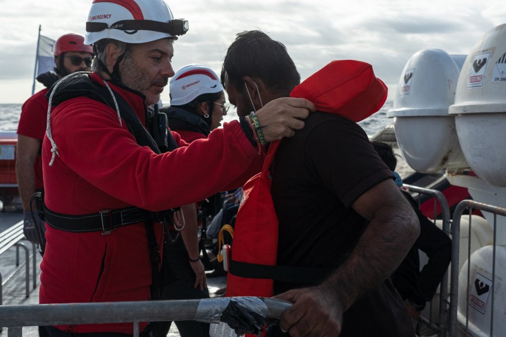 A crew member on board Life Support helps a rescued migrant with a life jacket | Photo: Press release Emergency NGO