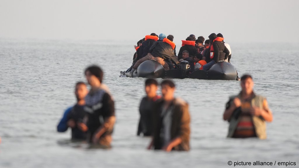 People in Channel waters up to their hips in front of a boat onto which people are crowded who are hoping to cross the Channel to the UK on July 17, 2025 | Photo: picture alliance/empics
