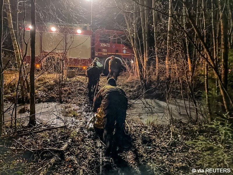 Polish officials transport a migrant towards a firefighting truck on the Polish-Belarusian border, Poland | Photo: Polish Territorial Defence Forces via REUTERS