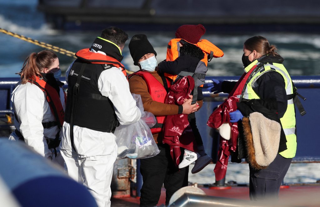Un migrant avec un enfant aux bras arrive au port de Douvres, après avoir traversé la Manche à bord d'un petit bateau, le 13 janvier 2022. Crédit : Reuters