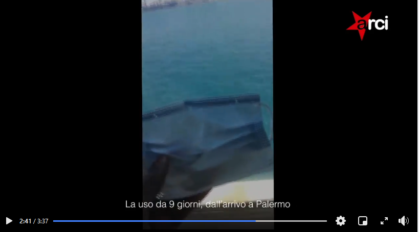 A screenshot of the asylum seeker holding up his disposable mask in front of the view from his cabin | Source: Screenshot from video ARCI Facebook