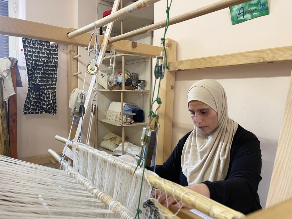 Amal Ahmad Okla fabrique des tapis et des sacs sur un métier à tisser. Crédit : InfoMigrants
