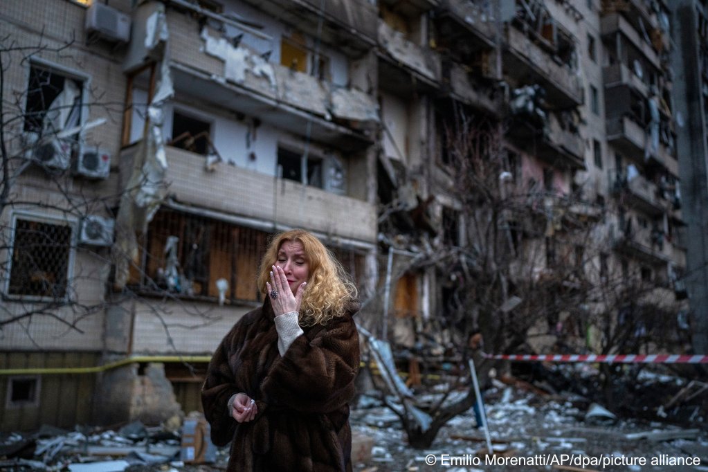 A woman in front of a building damaged by Russian missiles | Photo: Emilio Morenatti/AP/picture alliance