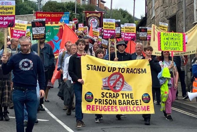 From file: The Dorset branch of the Stand up to Racism movement demonstrates against the Bibby Stockholm barge | Photo. X page @Tolpuddlefest