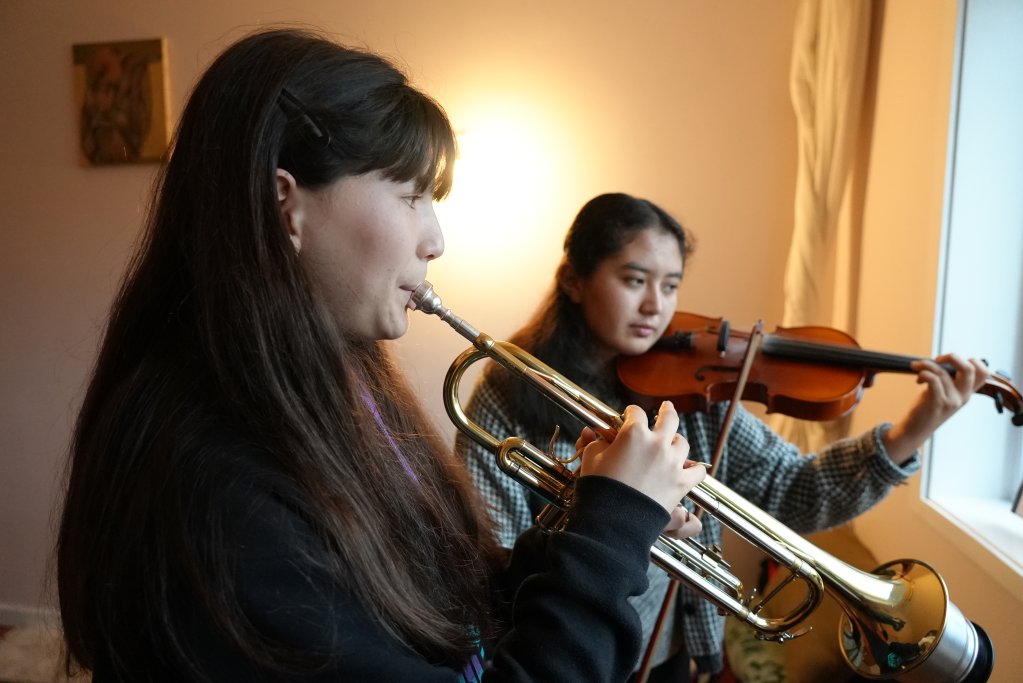 Zohra (à gauche, avec la trompette) et Farida (à droite, avec le violon) répètent dans leur chambre. Crédit : Claire Debuyser