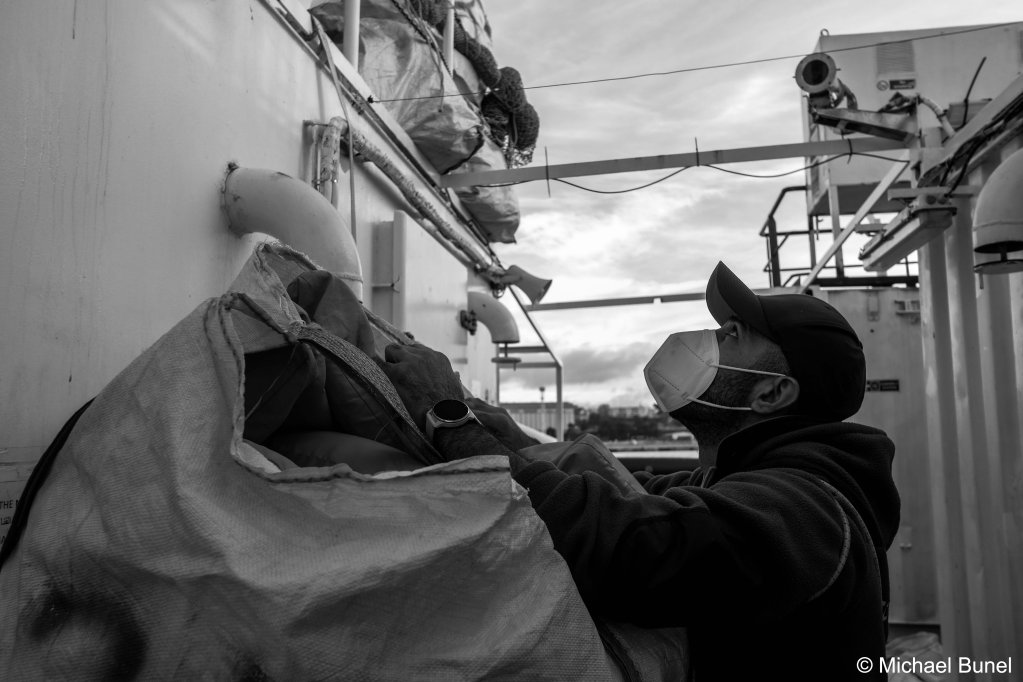Still at the quay in Marseille, teams are preparing the boat for departure. Astoun on the bridge passes a bag full of life jackets to his colleague Hector on the upper deck. December 16, 2022 | Photo: Michael Bunel